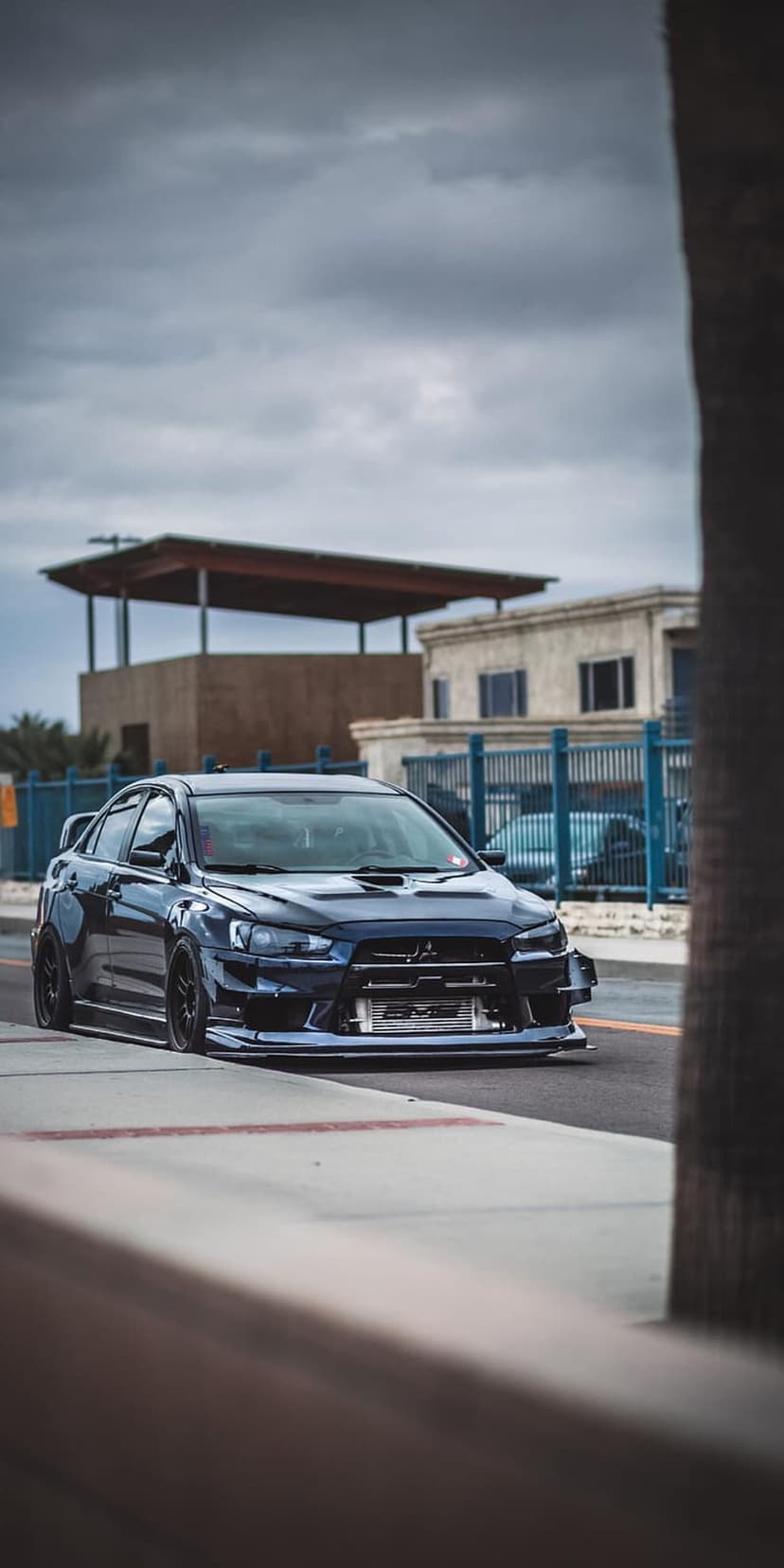 Dark blue Mitsubishi Lancer Evo with wide body kit and front intercooler parked on an urban street.
