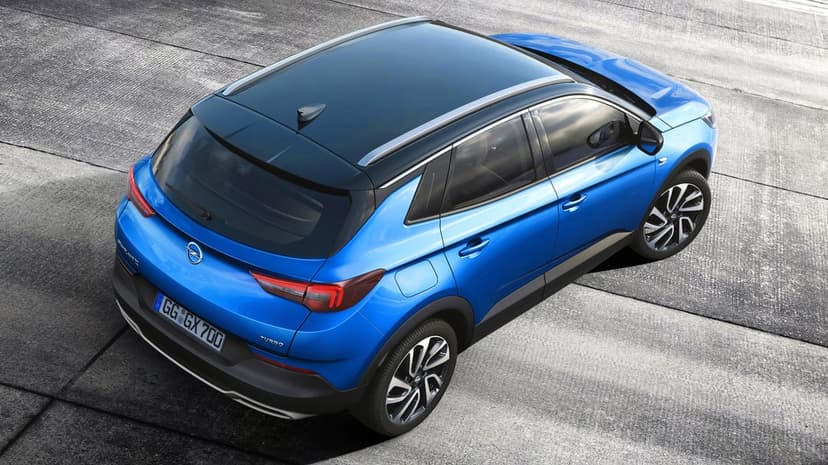 Blue Opel Grandland X SUV with a black roof parked on gray concrete viewed from a high-angle rear perspective.