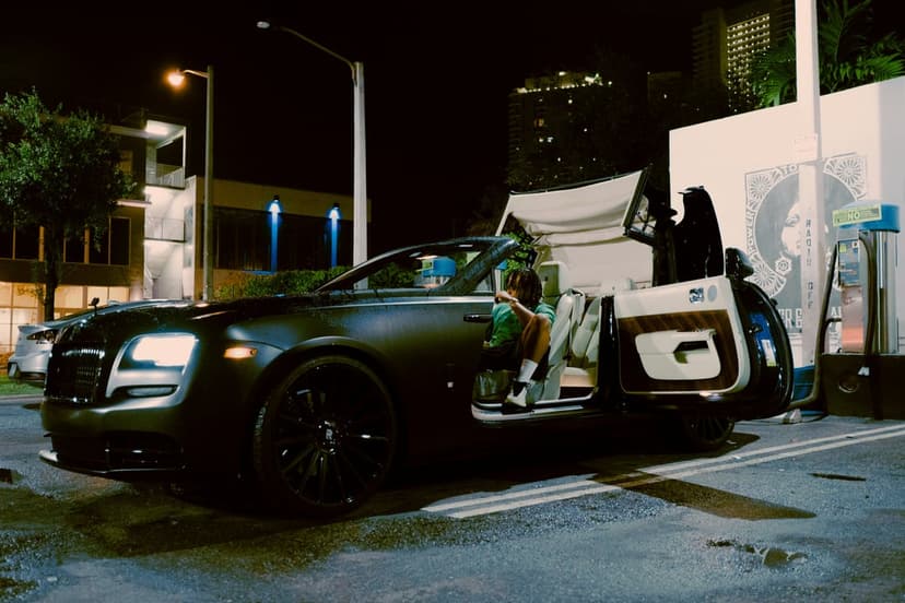 Rolls-Royce convertible with open doors and a white leather interior parked on a city street at night with lights.