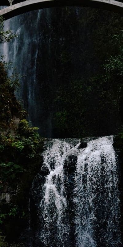 Beneath the Arch- Cascading Waters of a Lush Waterfall