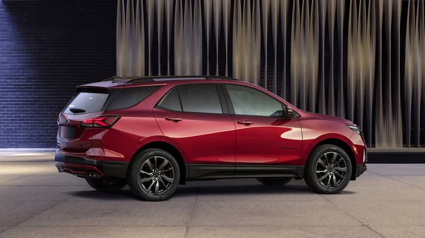 Red Chevrolet Equinox SUV parked beside a modern brick wall with vertical slats under soft studio lighting.