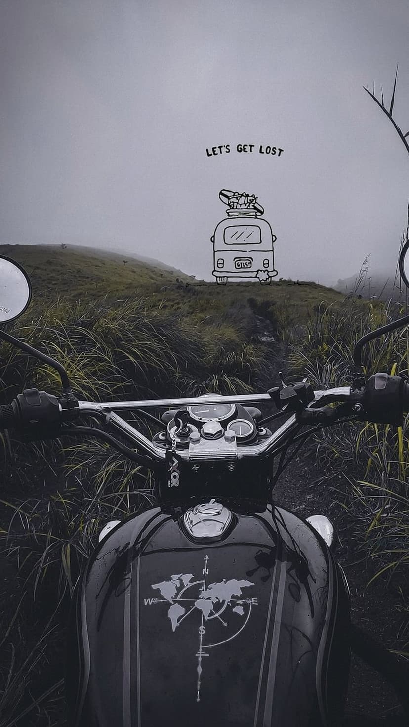 Motorcycle on a dirt trail overlooks misty mountains with a world map tank and a let's get lost graphic.