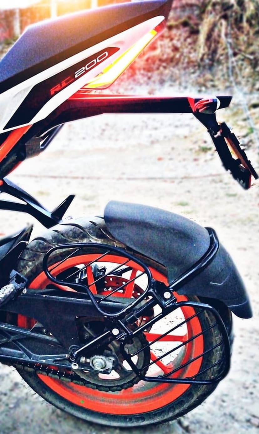KTM RC 200 motorcycle rear wheel with an orange rim, black fender, and tire on a gravel outdoor surface.