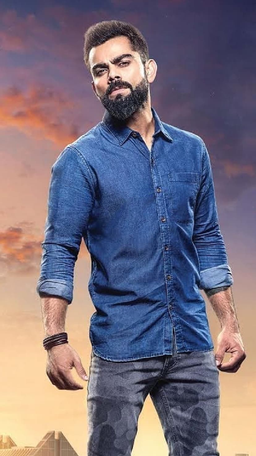 Virat Kohli wearing a denim shirt and camouflage pants stands before a dramatic sky in a vertical fashion portrait.