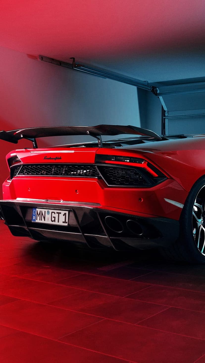 Red Lamborghini Huracan GT rear view with a large spoiler and glowing taillights under blue and red garage lights.