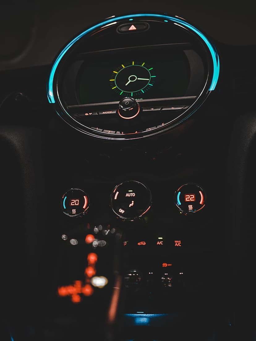 Illuminated car dashboard features a blue neon LED ring around a clock and glowing temperature control knobs.
