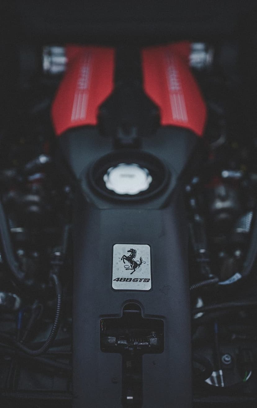 Red Ferrari 488 GTB engine covers featuring the prancing horse insignia and intricate mechanical components.