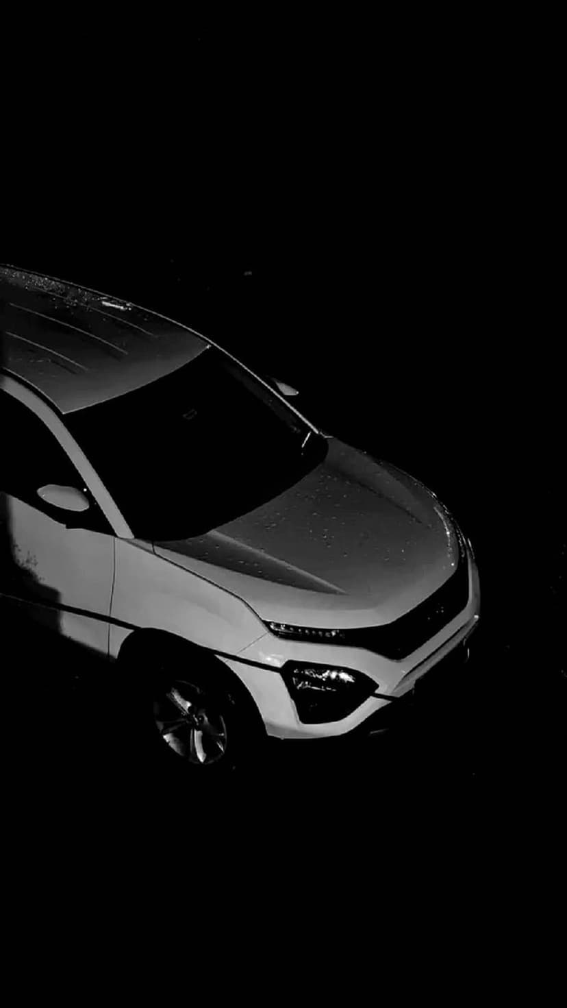 White SUV hood covered in glistening raindrops during a rainy night, viewed from a high-angle monochromatic perspective.