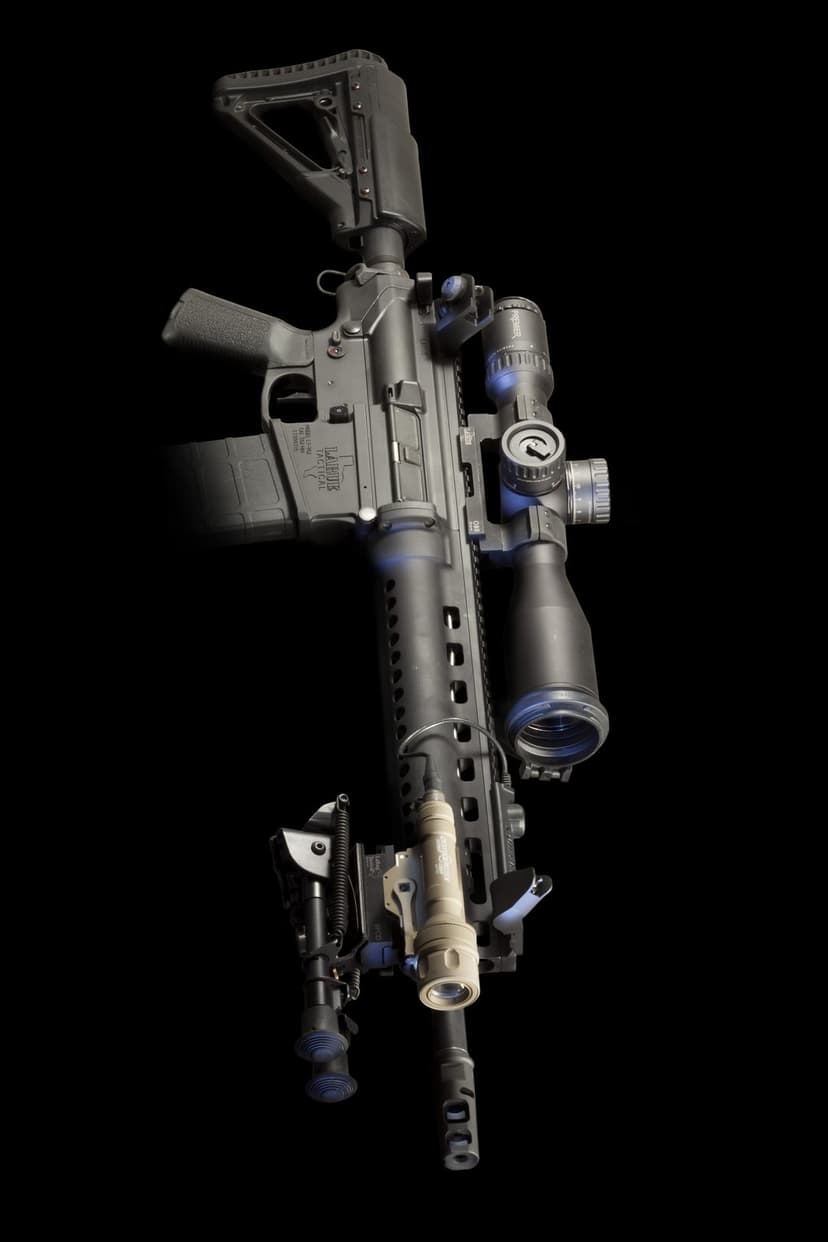 Black AR-15 rifle with a precision scope, tactical light, and bipod against a solid dark studio background.