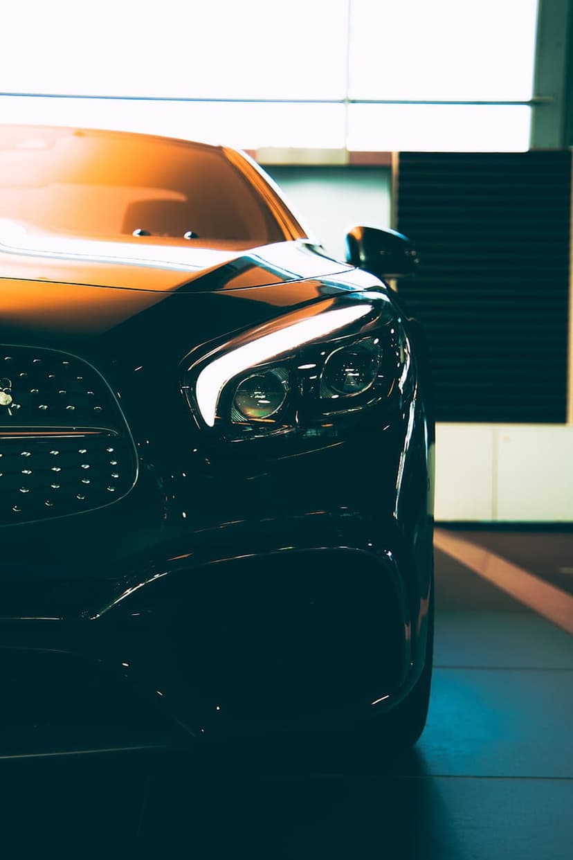 Black car headlight with bright LED accents and a textured mesh grille reflecting warm ambient light.