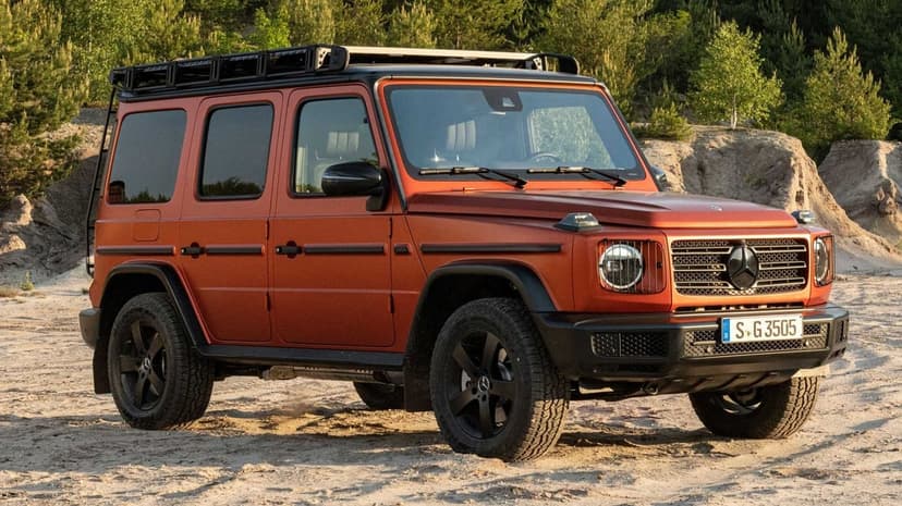 Orange Mercedes-Benz G-Class with a roof rack and black wheels parked in a sandy quarry with green trees.