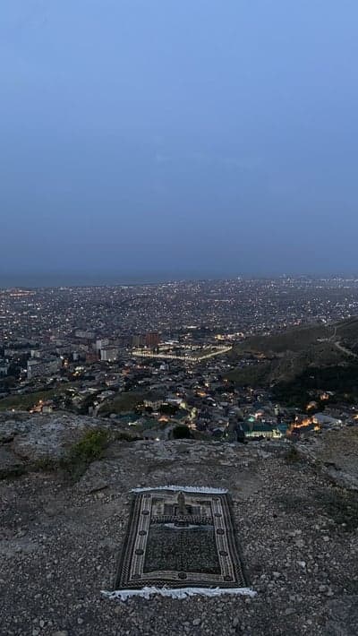 Praying Mat Overlooking City Lights at Dusk