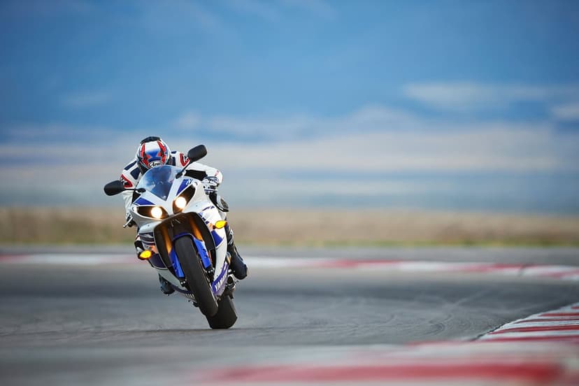 Yamaha YZF-R1 motorcycle racing on a track with a rider in full gear performing a high-speed lean and turn.