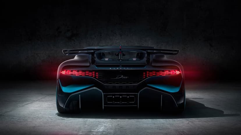 Rear view of a black Bugatti Divo with glowing red LED taillights and cyan accents in a dark concrete garage.