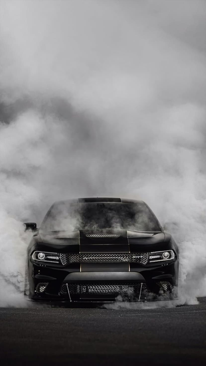 Dodge Charger muscle car front view shrouded in thick white tire smoke during a burnout in black and white.