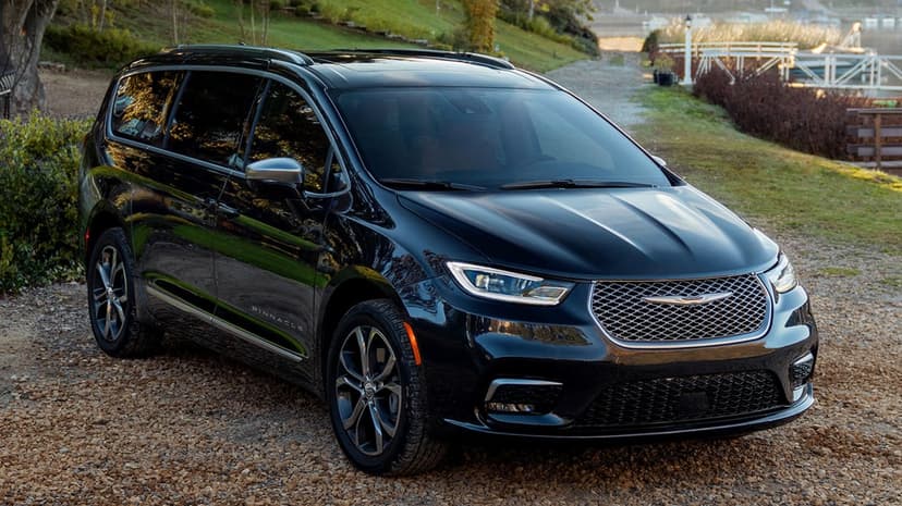 Black Chrysler Pacifica Pinnacle parked on gravel near a lake with warm golden hour reflections and chrome trim.