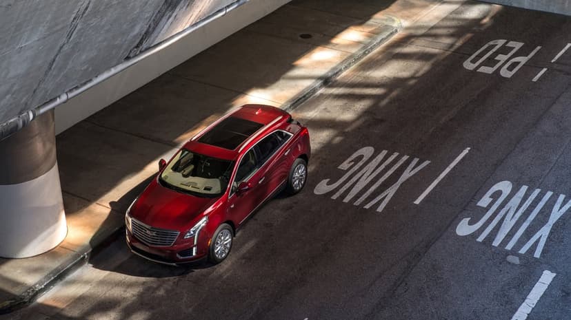 Red luxury SUV parked in a sun-drenched urban tunnel with bold white pedestrian crossing road markings.