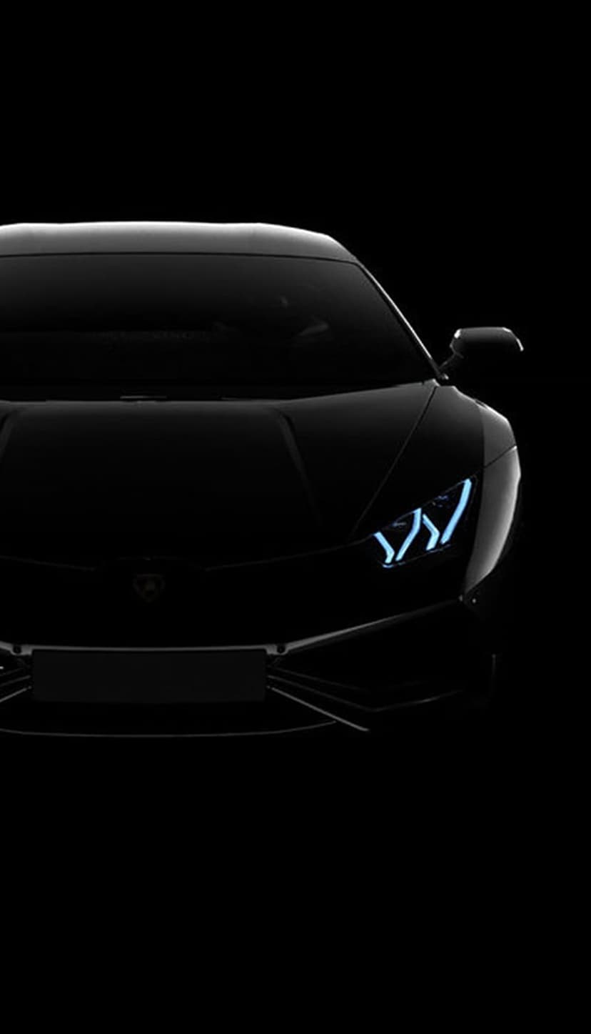 Lamborghini headlights emitting a bright blue glow against a dark chassis and background with sharp body lines.