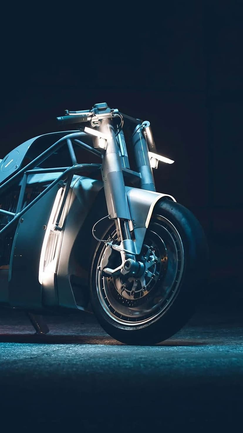 Electric motorcycle with glowing blue LED strips on the front forks and a large alloy wheel in a dark setting.