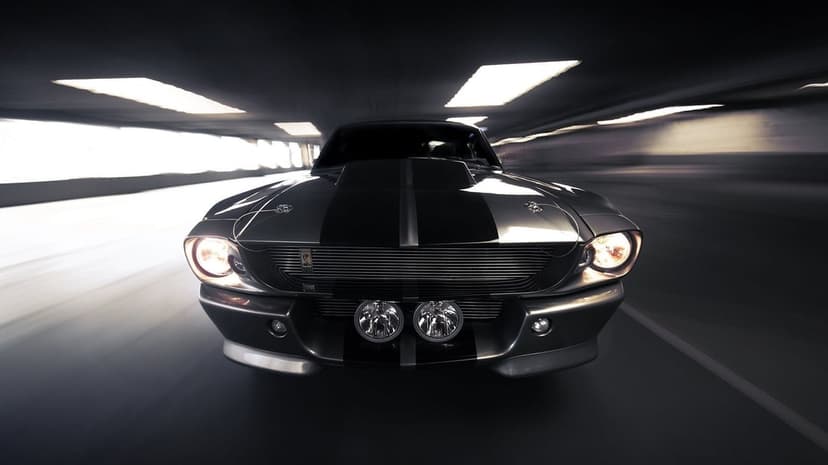 Silver Ford Mustang Shelby GT500 with glowing headlights racing through a motion-blurred dark tunnel.