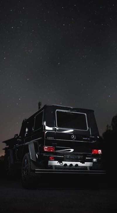 Black Mercedes G-Wagon under starry night sky
