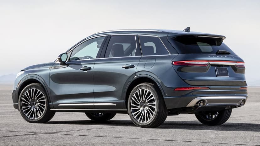Metallic blue luxury SUV parked on a flat gray surface with a clear sky in a rear-quarter landscape view.