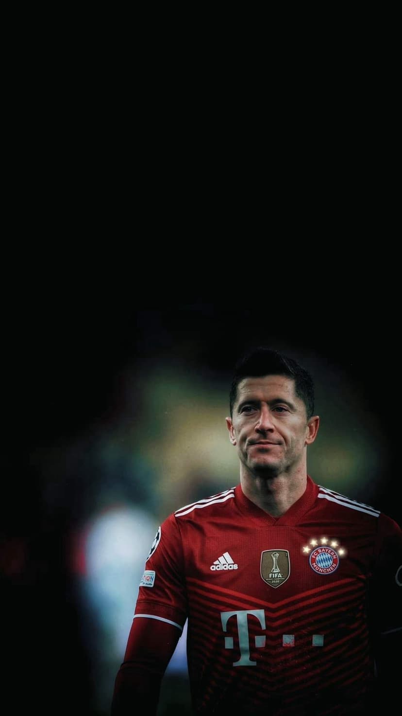 Robert Lewandowski wearing a red Bayern Munich jersey with an Adidas logo against a dark blurred background.