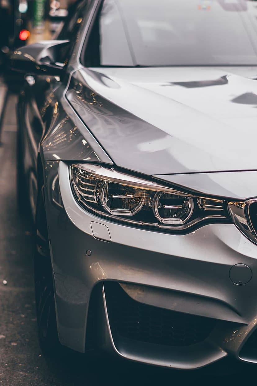 BMW M4 silver headlight assembly with circular LED elements and sharp bumper lines in a close-up portrait.