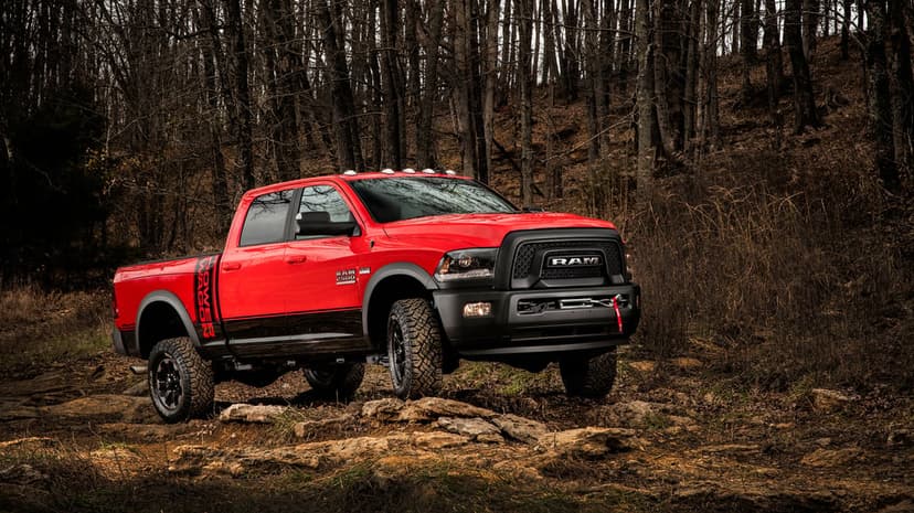Red Ram 2500 Power Wagon truck parked on a rocky off-road forest trail with bare trees in the background.