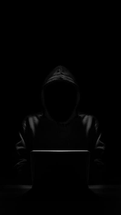 Anonymous Hacker in Dark Room with Laptop