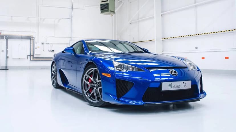 Blue Lexus LFA supercar parked in a bright white industrial studio with sleek metallic reflections and red calipers.