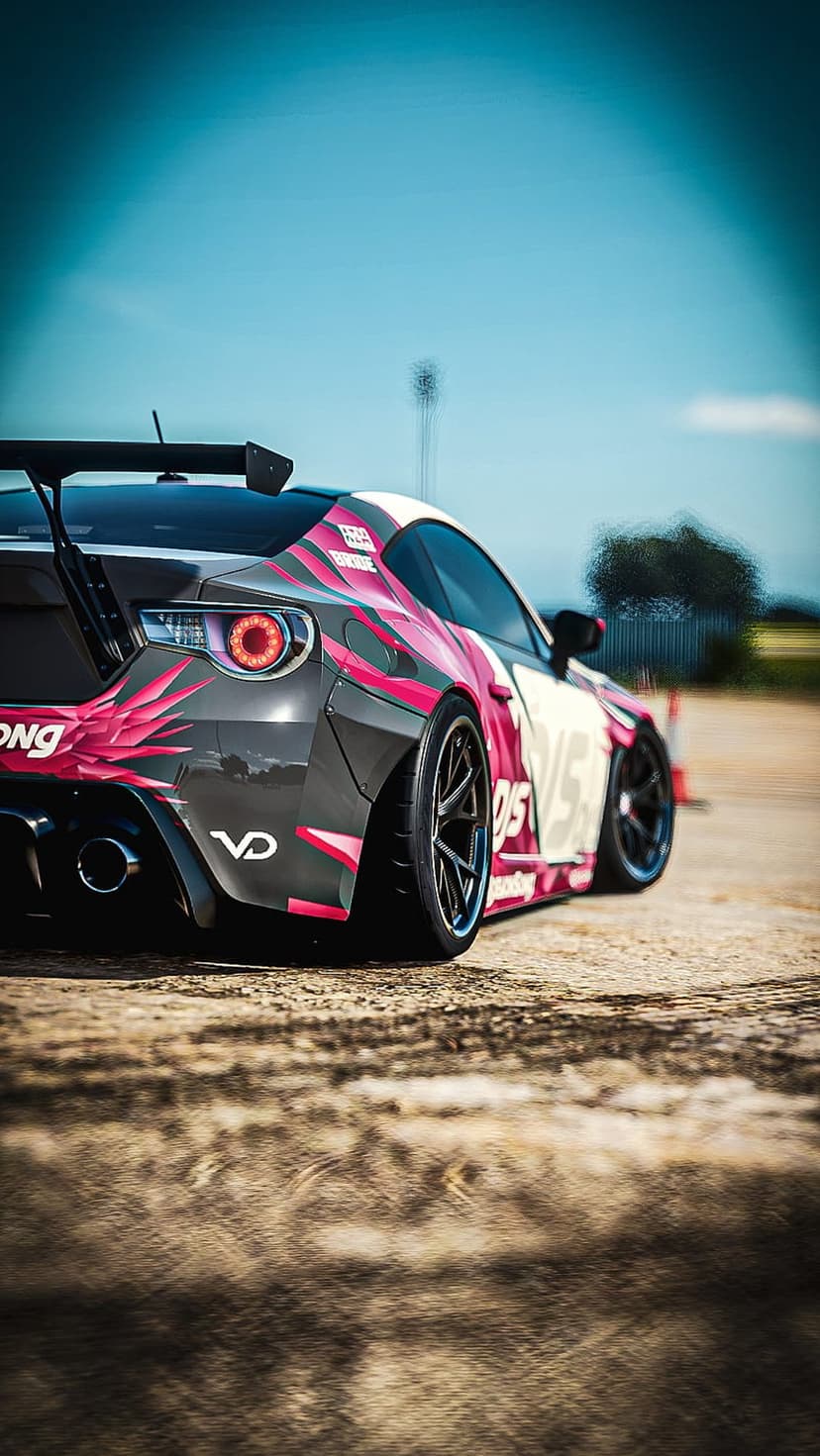 Subaru BRZ with pink graphics drifting on a dirt track under a blue sky with visible wheel motion blur.