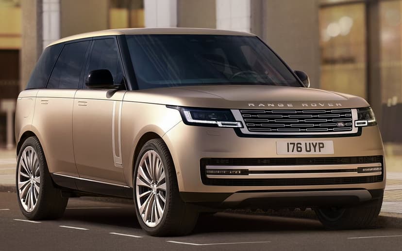 Gold Range Rover SUV with silver multi-spoke rims parked on a city street with soft sunlight reflections.