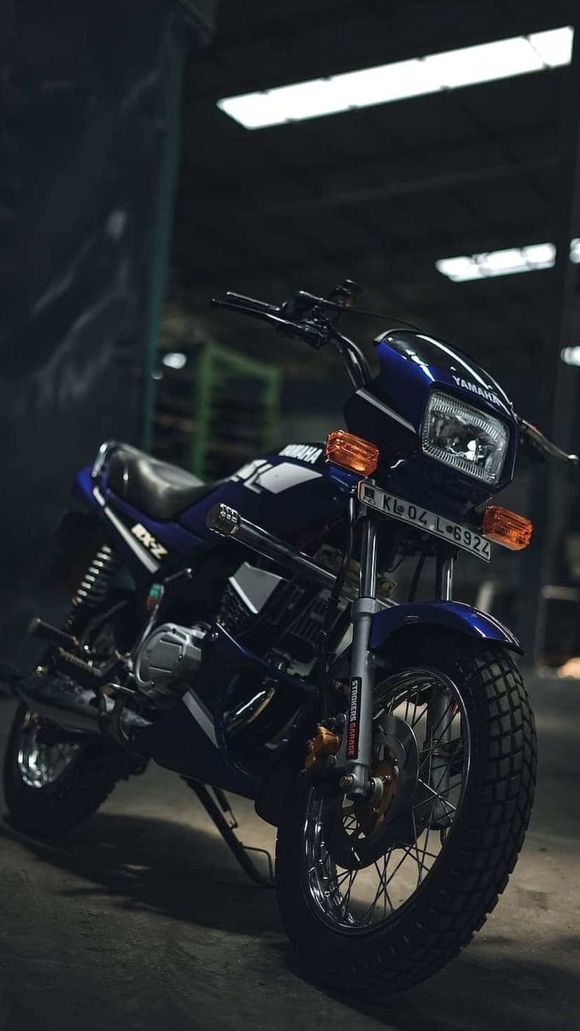 Yamaha RX-Z motorcycle in dark blue parked inside a dimly lit garage with subtle shadows and metallic highlights.