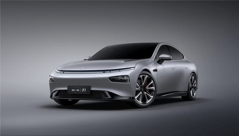 Silver XPeng P7 electric car with LED light bar and red brake calipers on a neutral grey studio background.