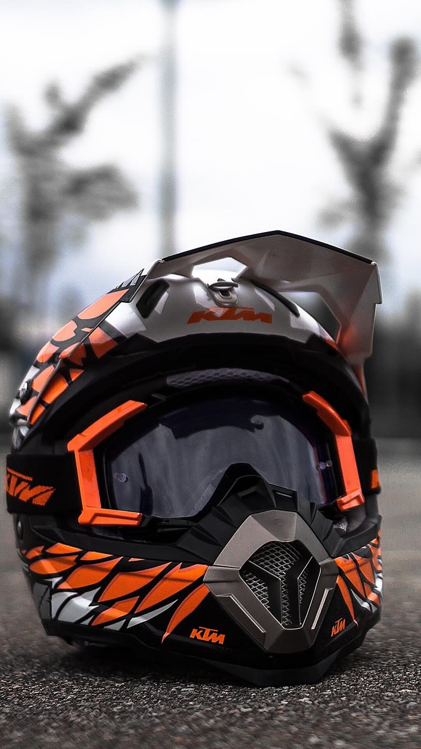 KTM motocross helmet features orange geometric graphics and a dark tinted visor for off-road racing protection.