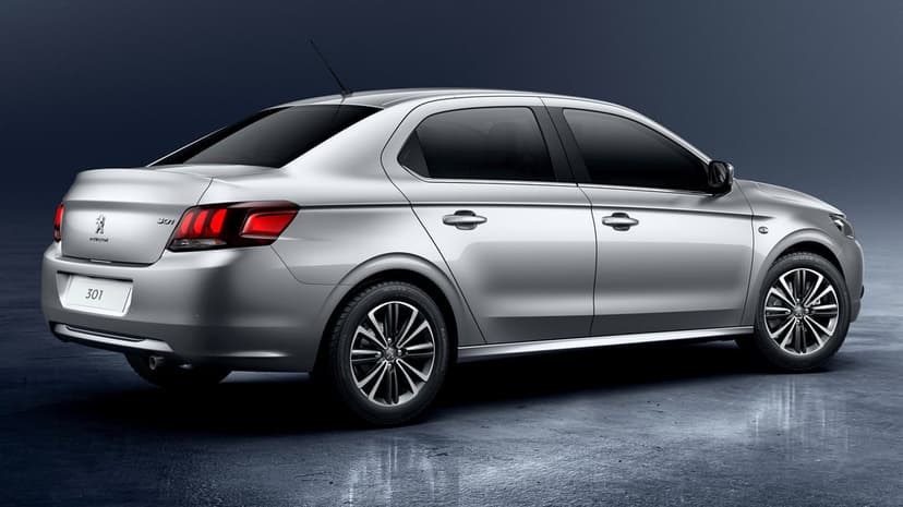 Silver Peugeot 301 sedan from rear angle in a dark studio with reflective floors and red taillights.