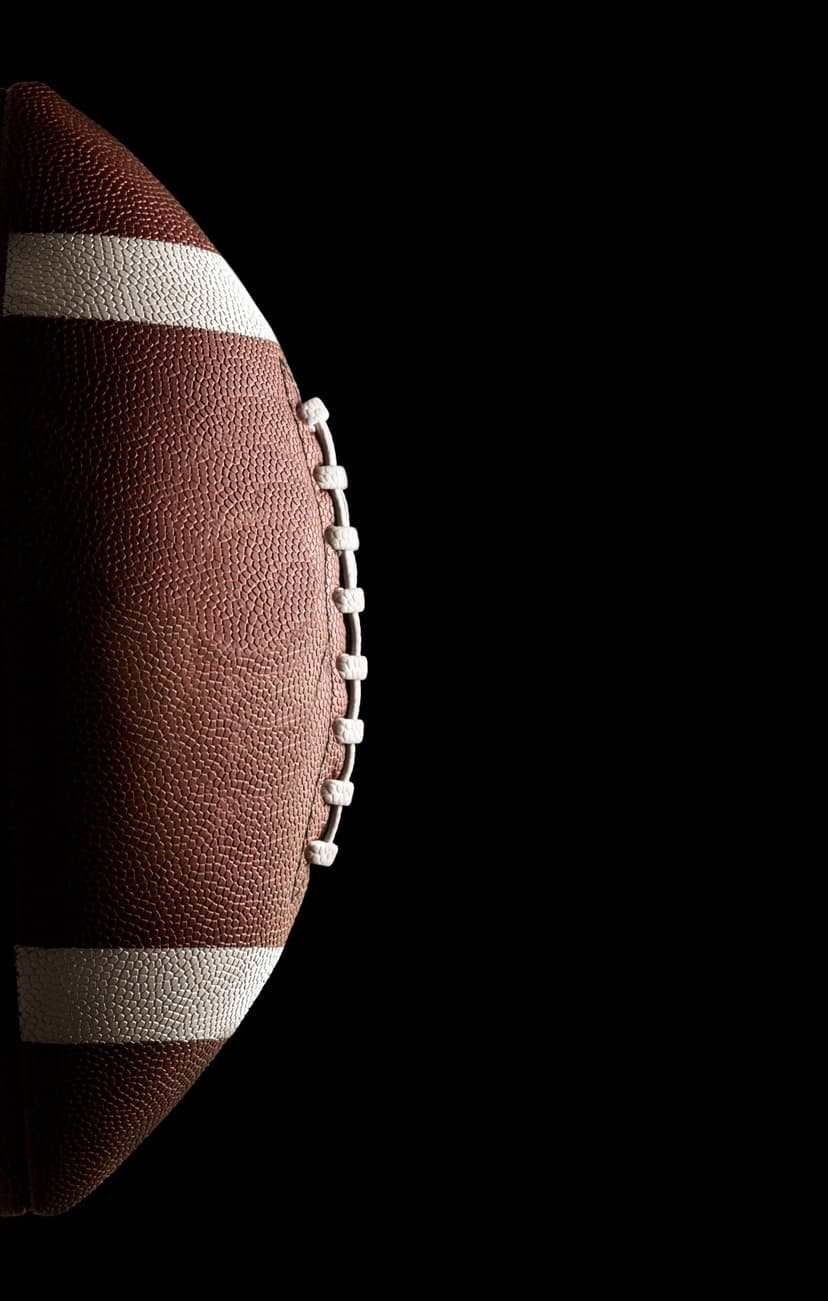 Brown leather American football with white laces and pebbled texture positioned against a solid black background.