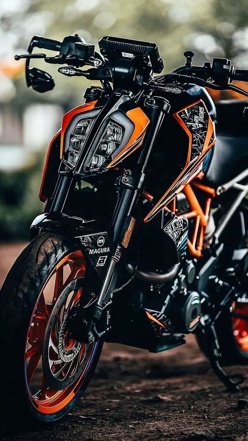 KTM Duke motorcycle front fork and orange wheel rim with an aggressive fairing against a blurred outdoor backdrop.