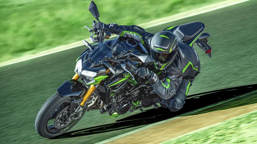 Black and lime green Kawasaki sports bike leaning deeply on a racetrack with a rider in matching gear.