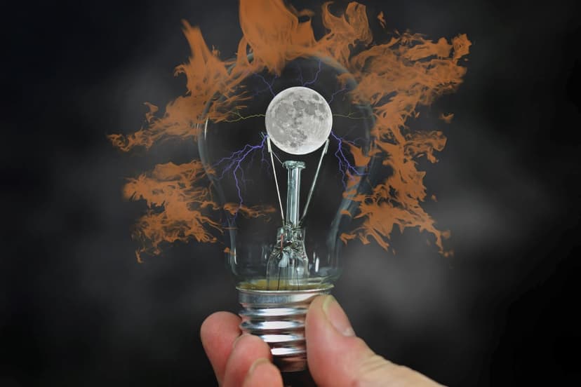 Hand holds a glass bulb containing a full moon with purple lightning amidst swirling orange fire and smoke.