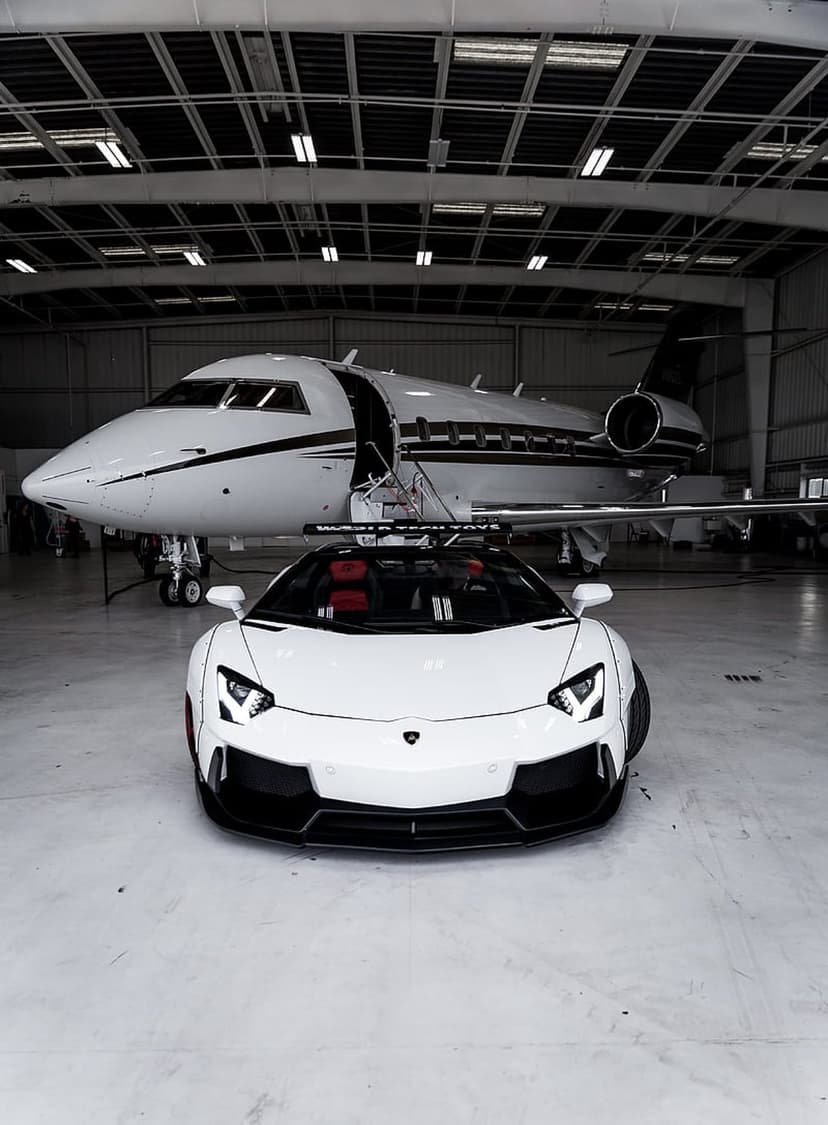 White Lamborghini Aventador parked in a modern hangar next to a large luxury jet with a polished engine cowling.