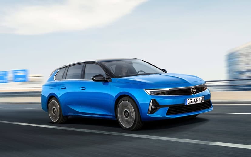 Blue Opel Astra Sports Tourer station wagon driving fast on a highway with motion blur background.
