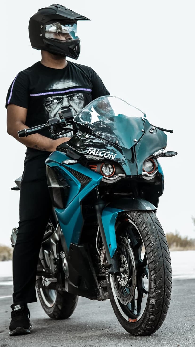 Man in a black helmet sits on a sapphire blue sportbike against a solid white background in this vertical view.