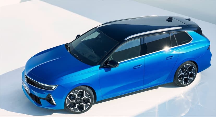 Electric blue estate car with a black roof and geometric wheels parked on a white floor in a bright studio.