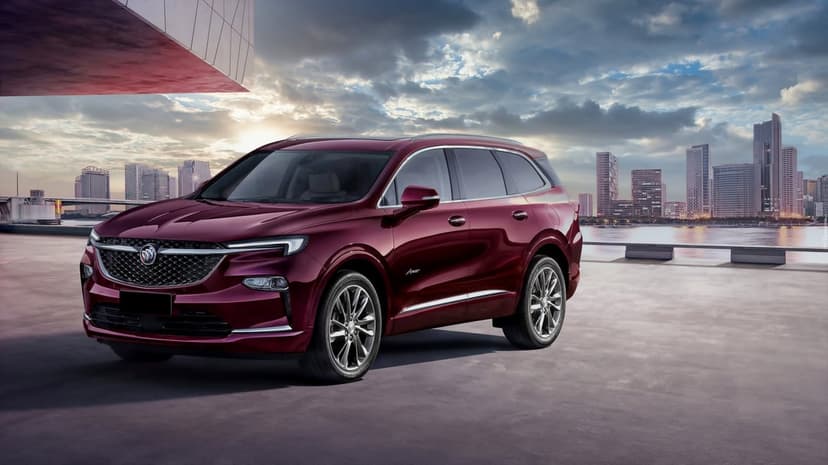 Maroon Buick SUV parked on a concrete terrace with a modern city skyline and dramatic sunset sky background.