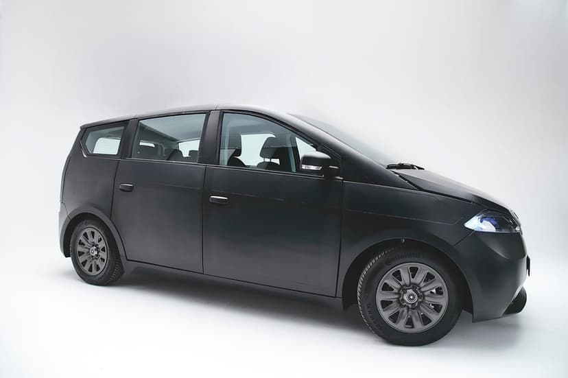 Matte black solar electric car in a white studio with integrated panels and gray alloy wheels.