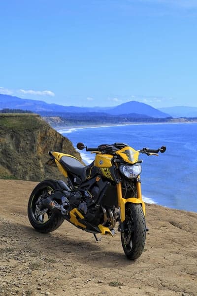 Yellow motorcycle parked on a cliff overlooking the ocean