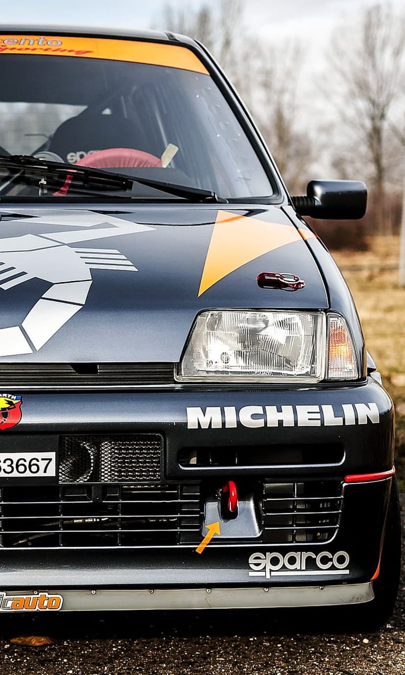Abarth rally car front grille with a dark blue finish, Michelin branding, Sparco logo, and orange tow hook.