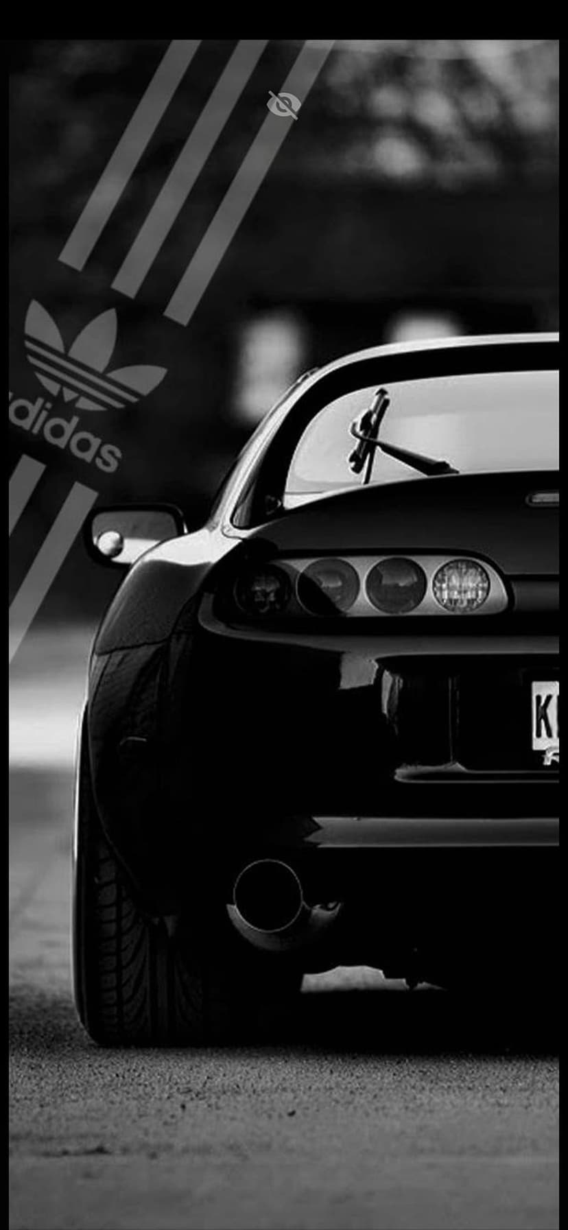 Rear view of a black sports car featuring white triple stripes and logo in a high-contrast monochrome setting.